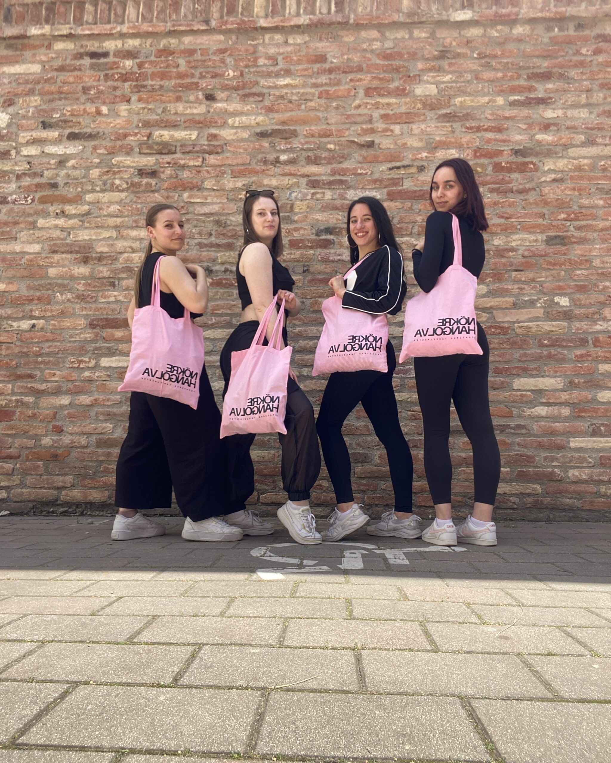 Résztvevők rózsaszín Nőkre Hangolva táskával a téglafal előtt